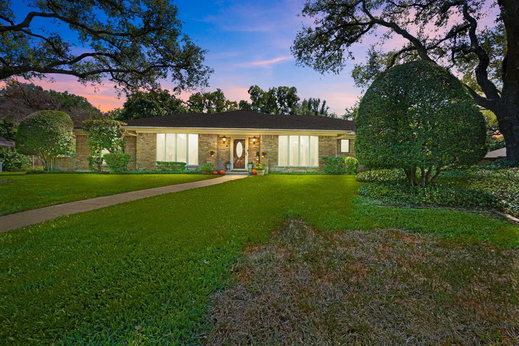 a front view of a house with a yard and trees