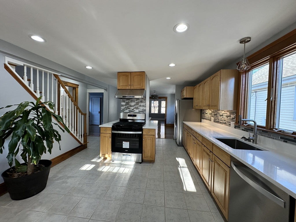 a kitchen with stainless steel appliances kitchen island granite countertop a stove a sink and a refrigerator