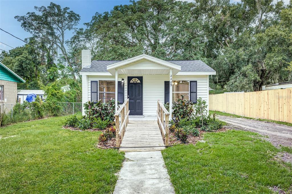 a front view of a house with a yard and potted plants