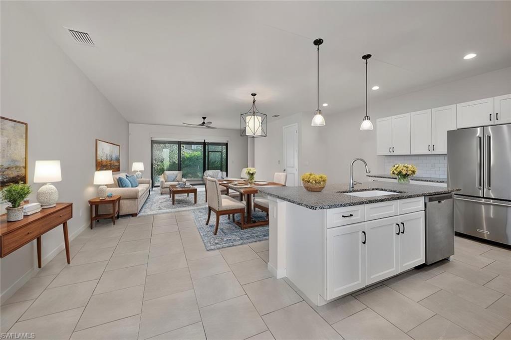 a kitchen with kitchen island granite countertop a sink a counter top space and living room view