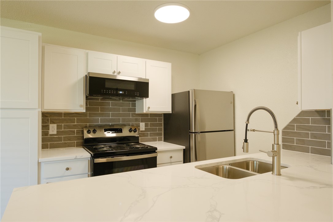 Kitchen featuring white cabinetry, appliances with