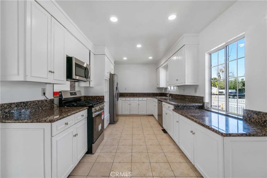 a large kitchen with stainless steel appliances granite countertop a sink and cabinets