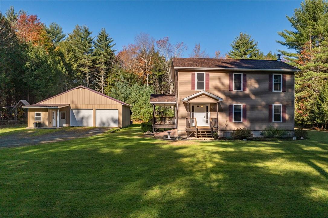 Colonial inspired home featuring a garage, a front lawn, and an outbuilding