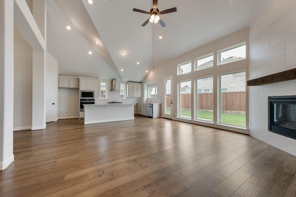 a view of an empty room with wooden floor and a kitchen