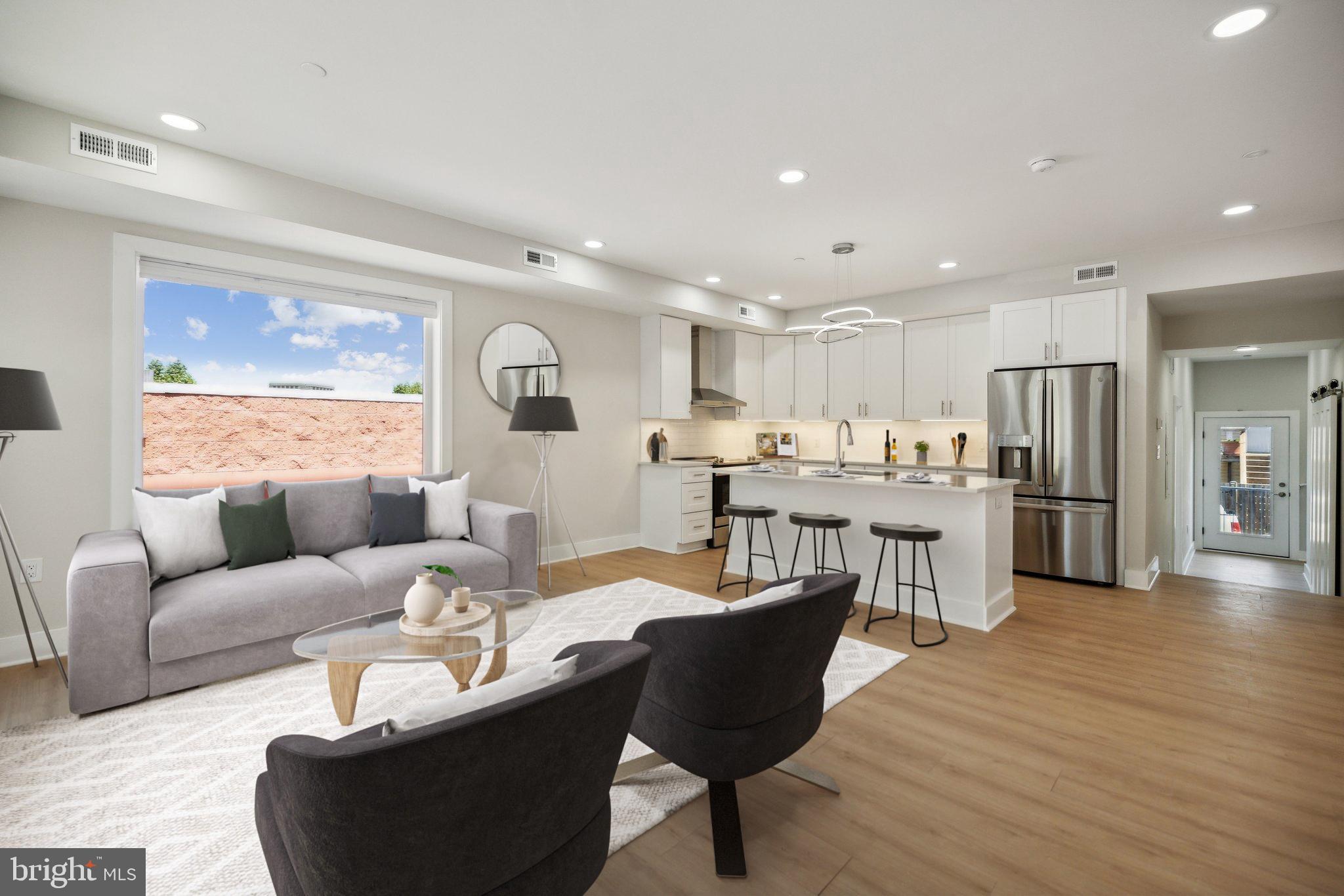 a living room with furniture and kitchen view with wooden floor