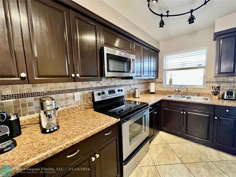 a kitchen with granite countertop stainless steel appliances a sink dishwasher a stove top oven a sink and cabinets