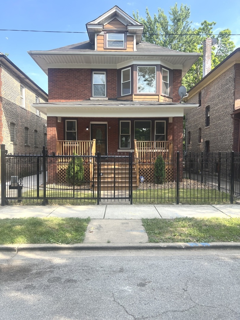 a brick house in front of a yard with a small garden