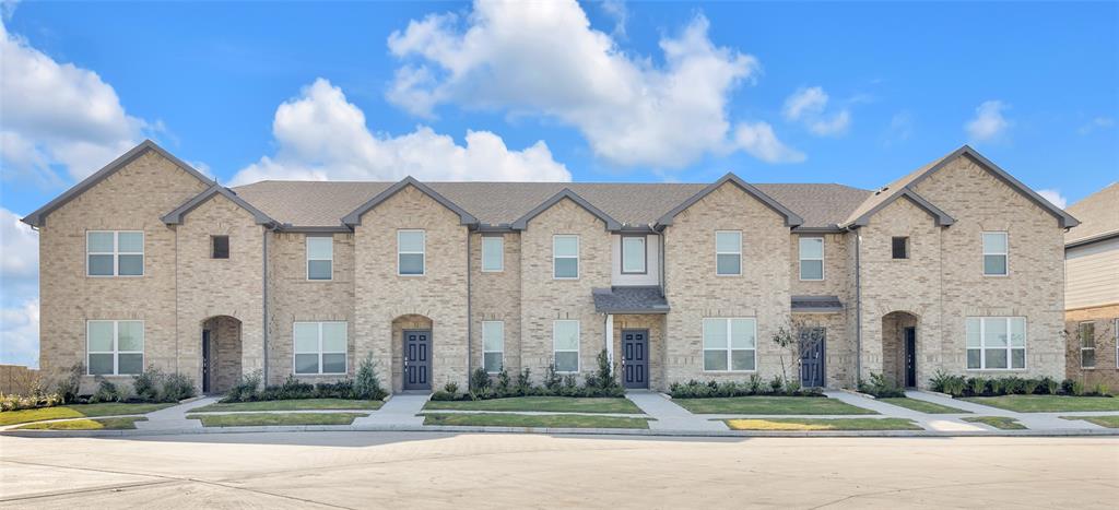 This is a modern townhouse complex featuring symmetrical brick exteriors, well-manicured lawns, and a welcoming, uniform design with individual entrances for each unit.