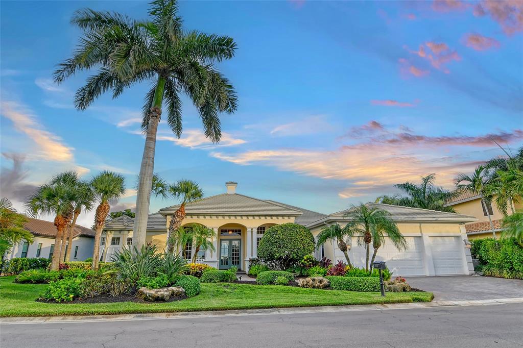 a front view of a house with a yard and palm trees