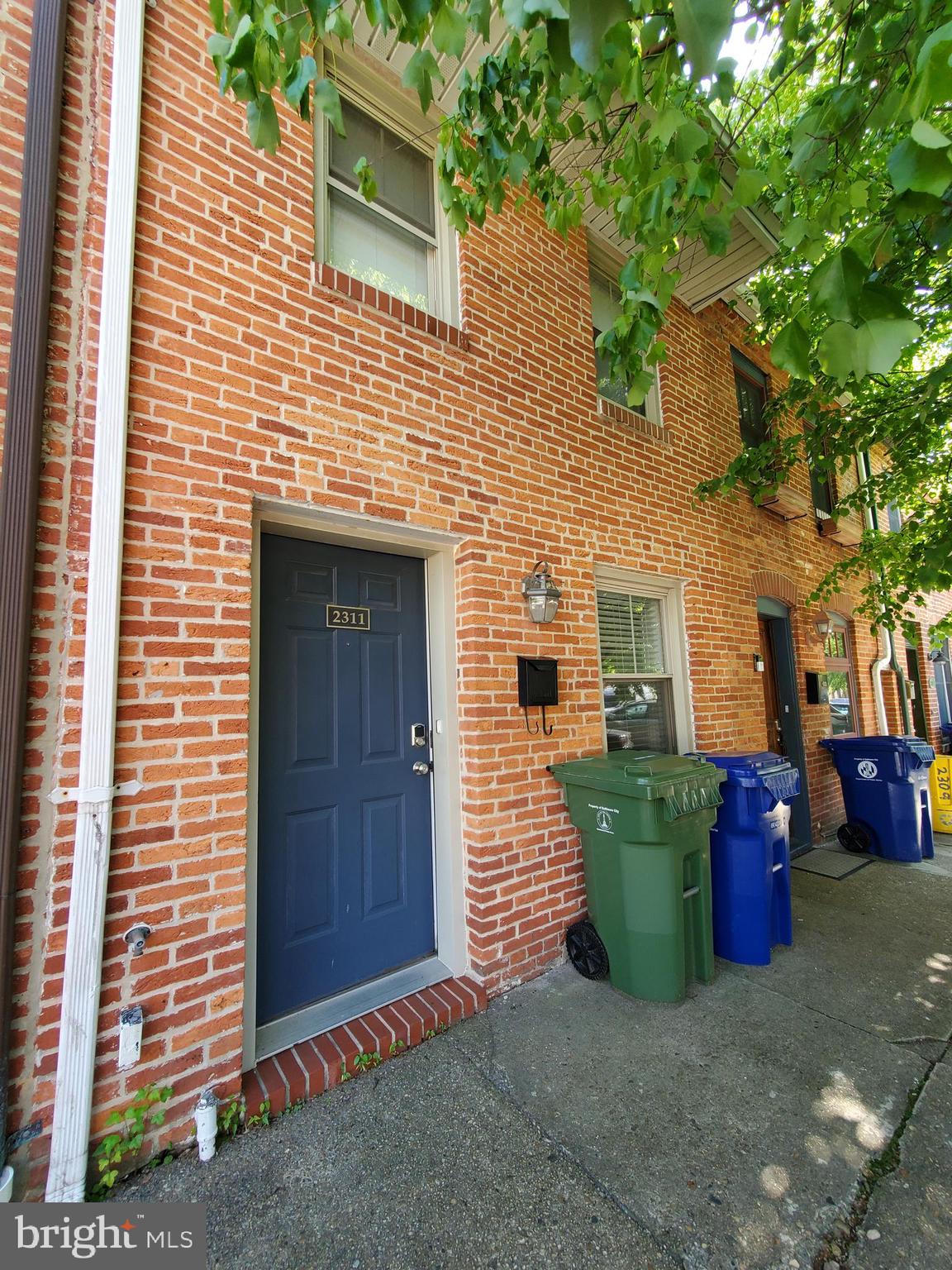 a view of a brick house with chairs and a yard