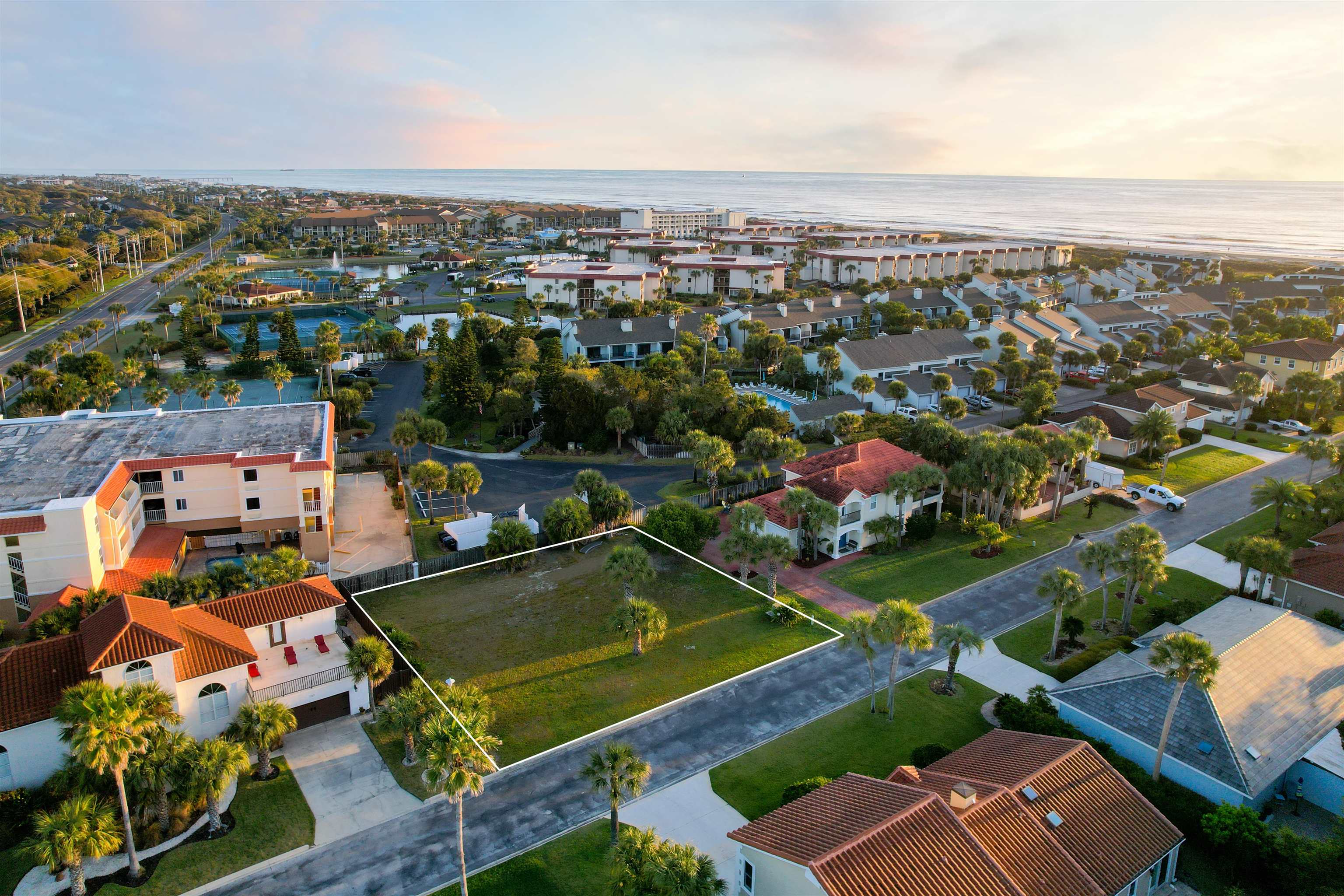 an aerial view of a resort with swimming pool tennis courts and ocean view