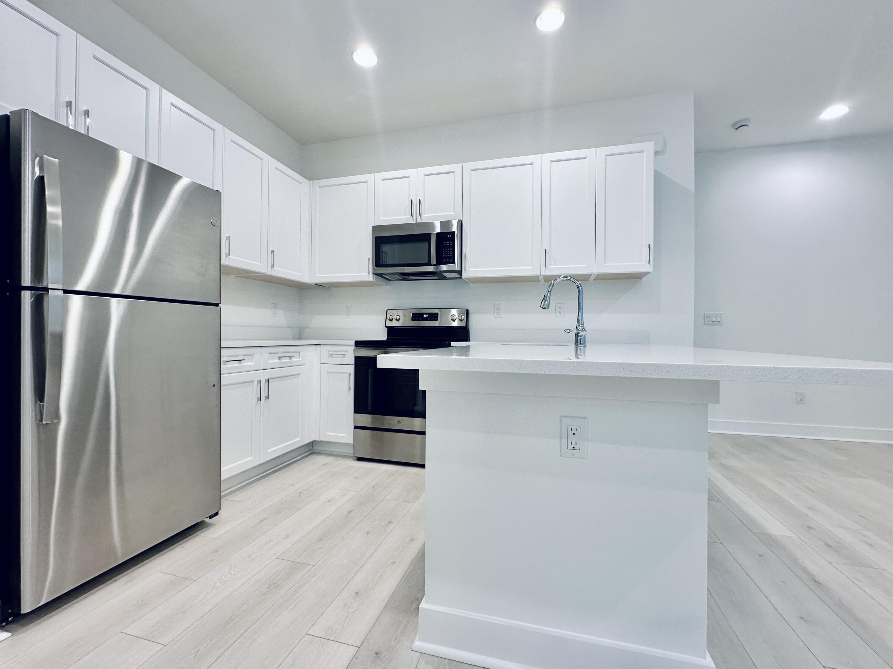 a kitchen with stainless steel appliances a refrigerator sink and white cabinets