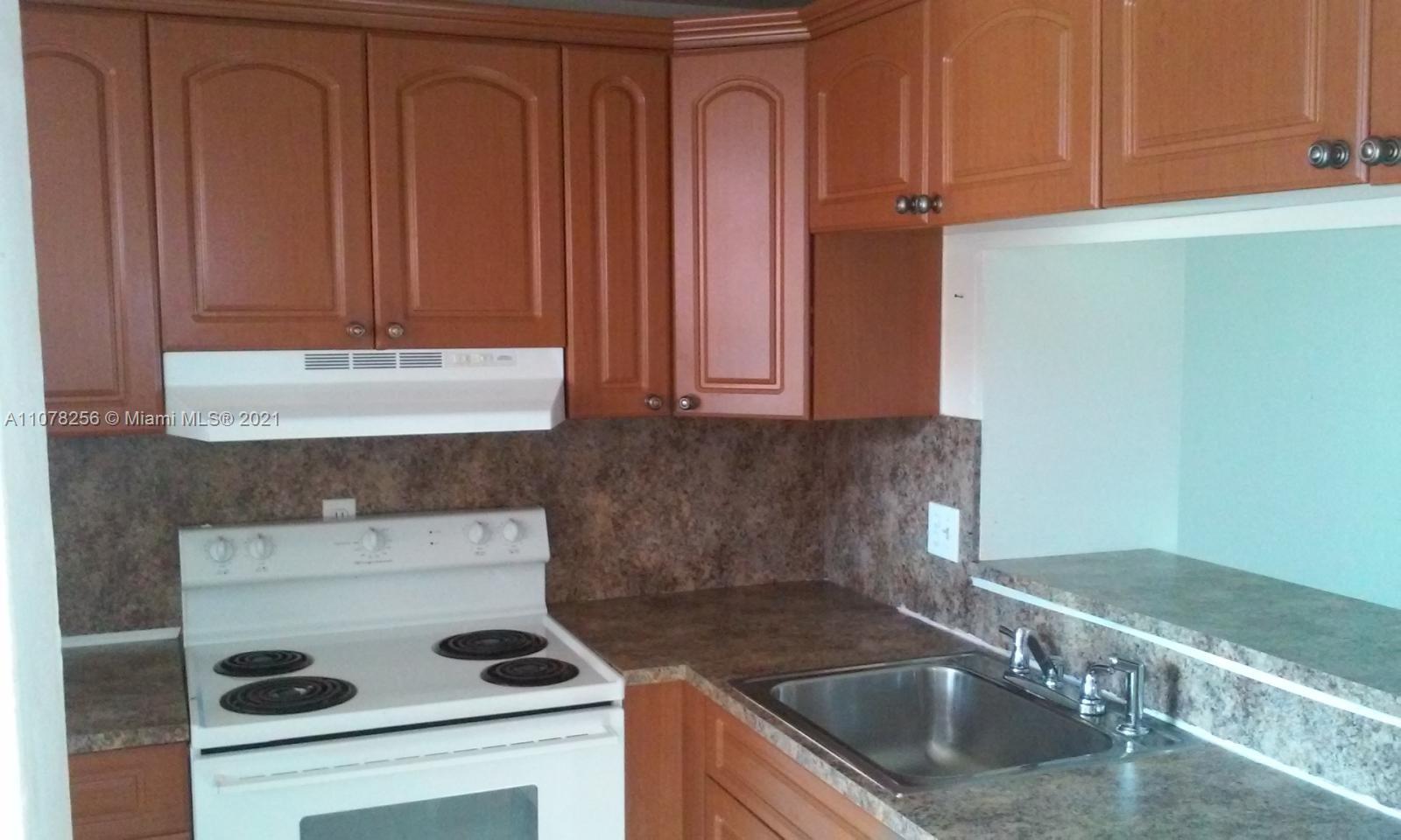 a kitchen with granite countertop a sink a stove and cabinets