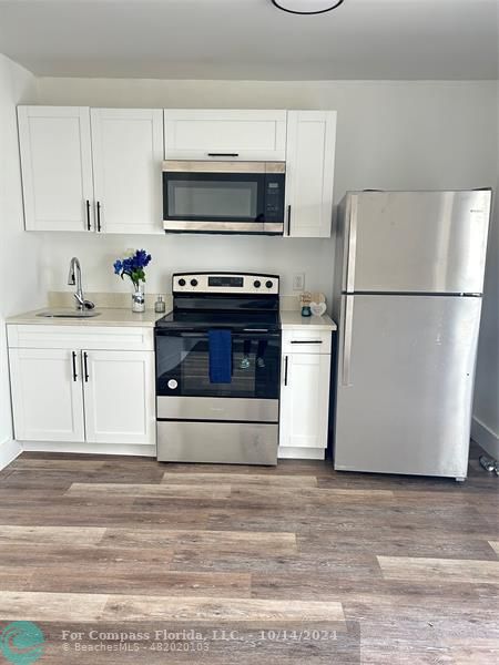 a white kitchen with a sink and a refrigerator