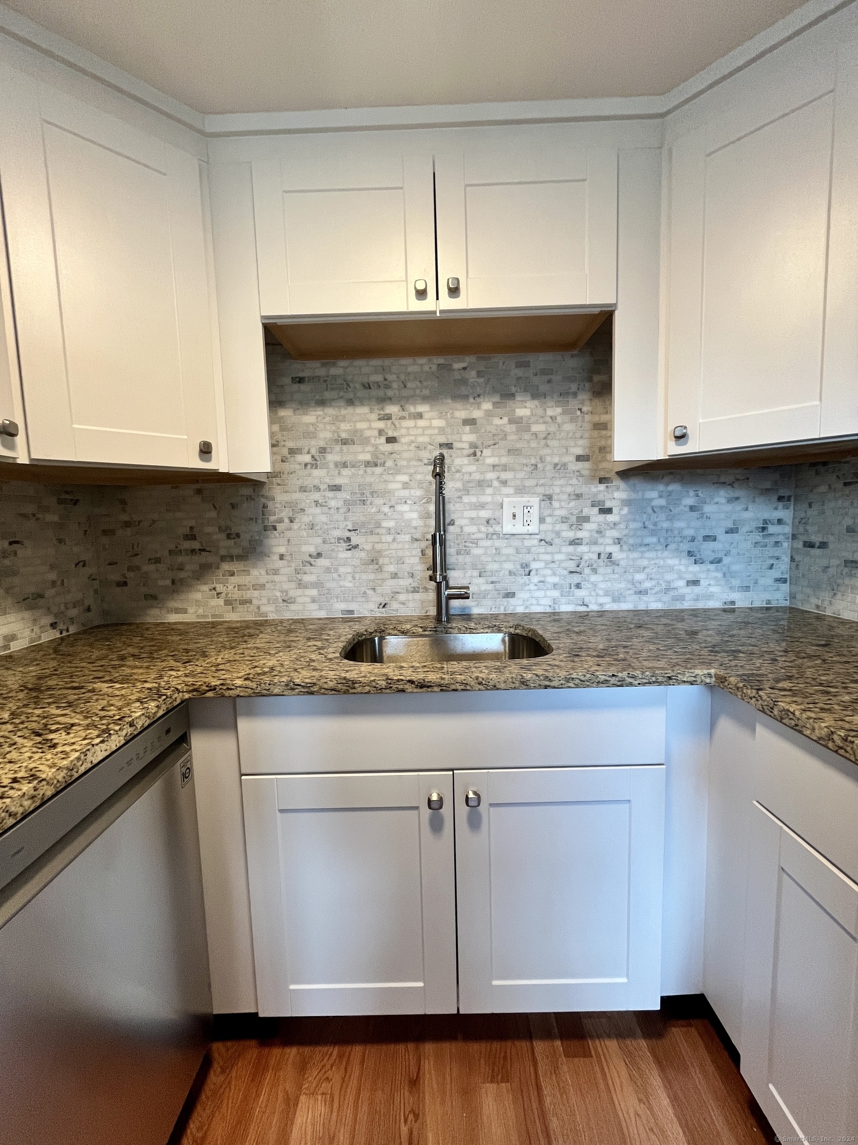 a kitchen with granite countertop white cabinets and a sink