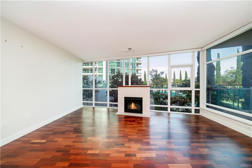 an empty room with wooden floor fireplace and windows