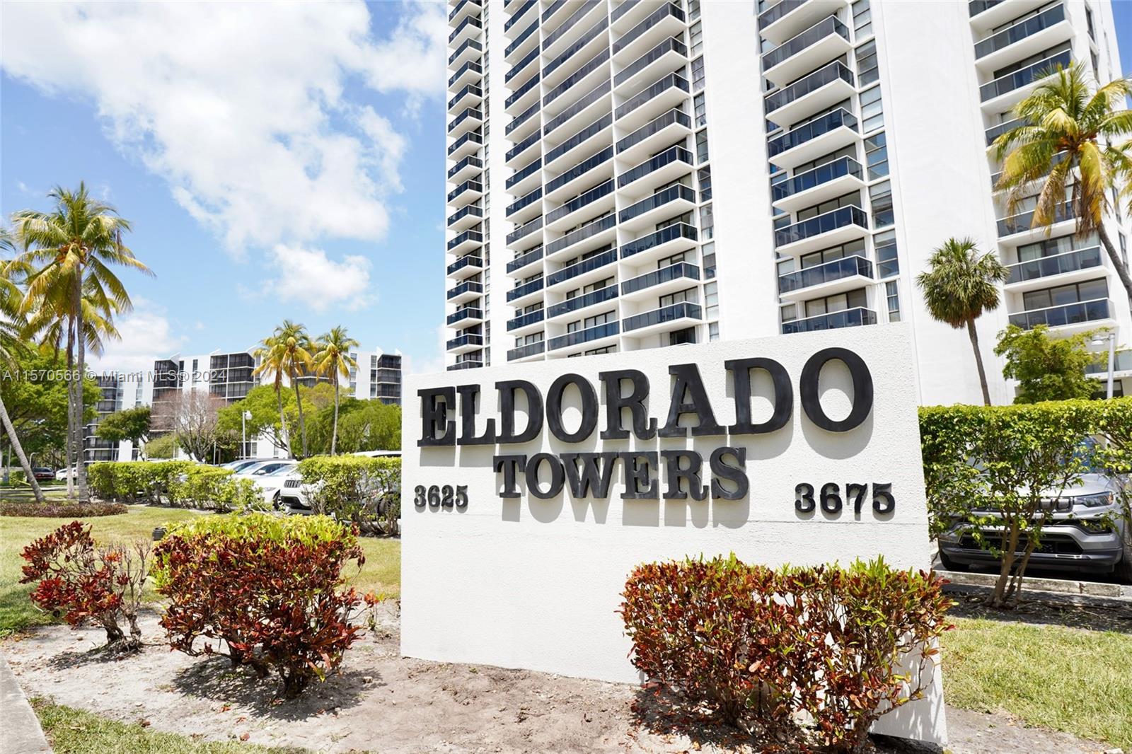 a view of a sign board with buildings in the background