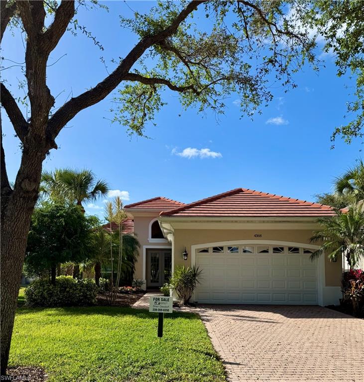 View of front of property with french doors, a garage, and a front lawn