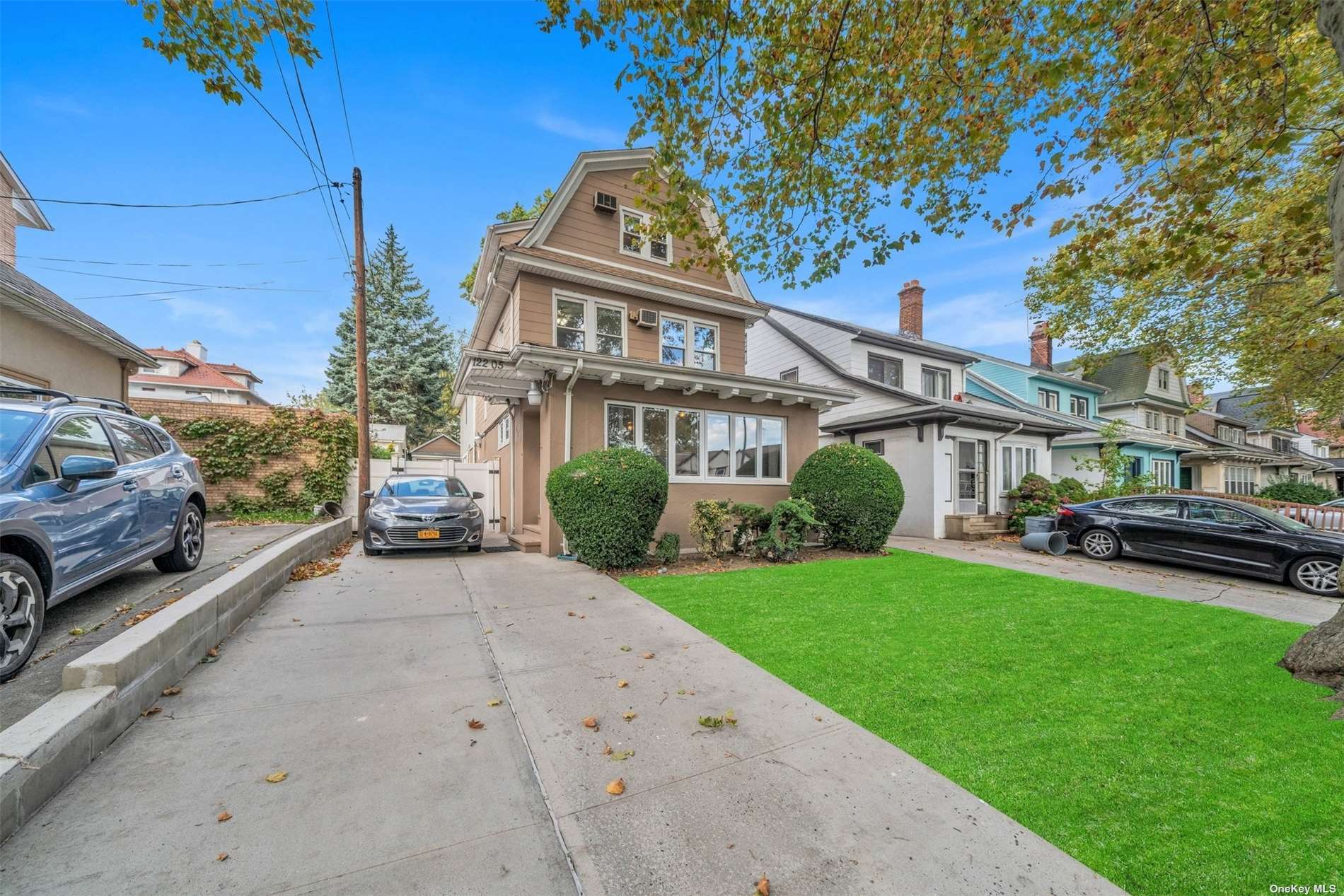 a view of a house with a cars park side of a road