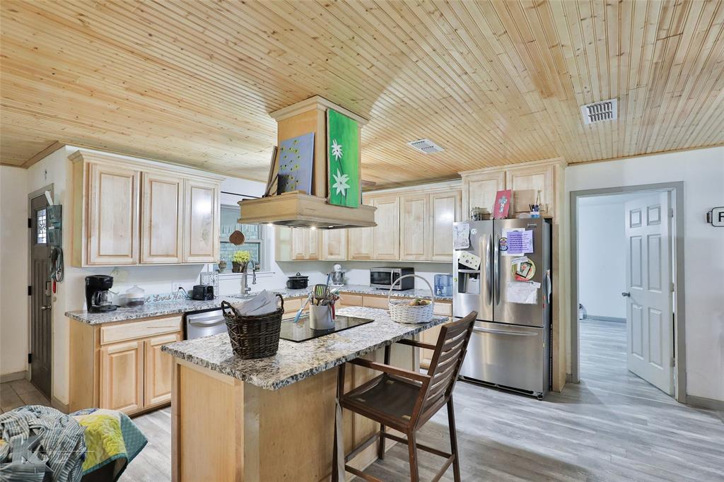 a kitchen with stainless steel appliances kitchen island granite countertop a table chairs in it and a window