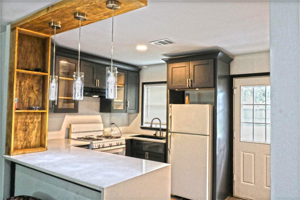 a kitchen that has a refrigerator a stove and white cabinets with wooden floor