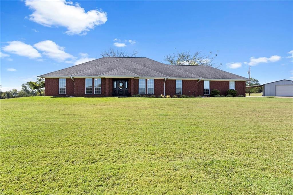 Rear view of property with a lawn, an outbuilding, and a garage