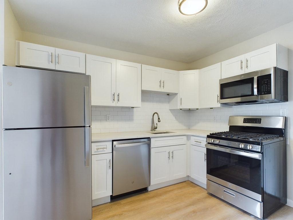 a kitchen with a refrigerator sink and white cabinets