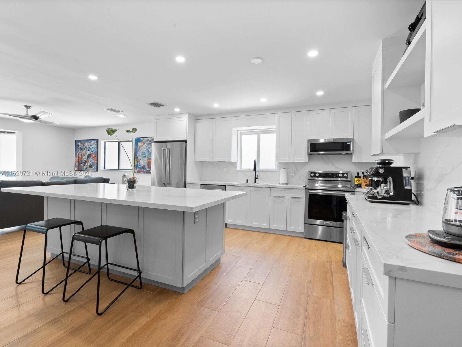 a kitchen with stainless steel appliances kitchen island granite countertop wooden floors and white cabinets