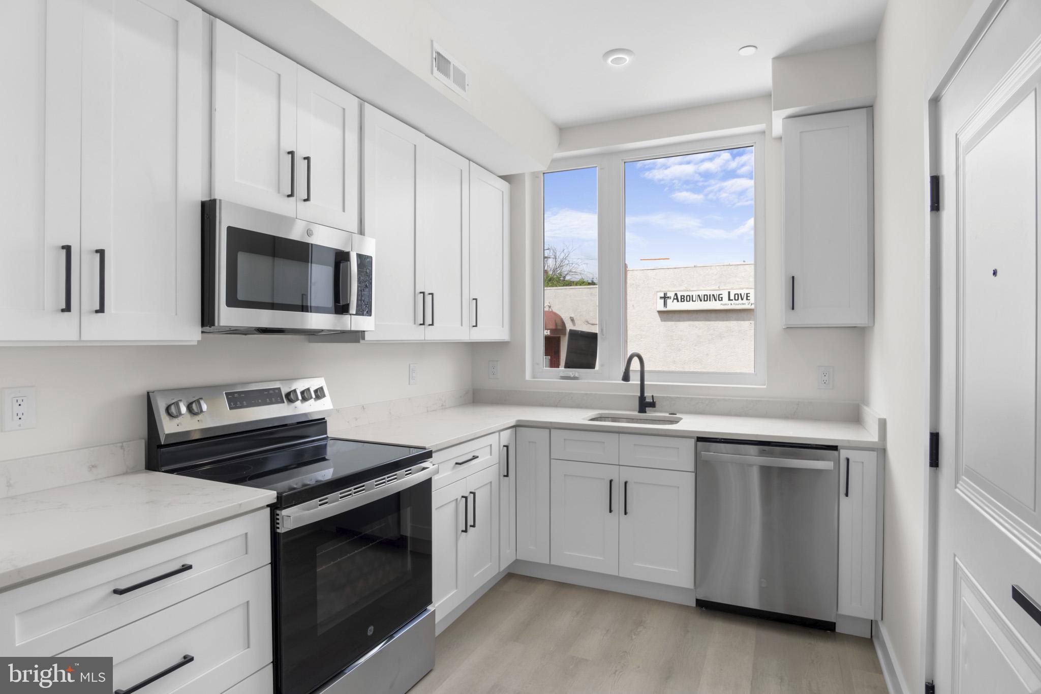 a kitchen with white cabinets appliances a sink and a window