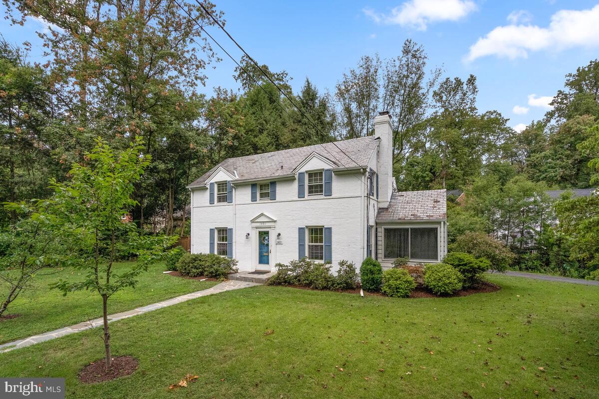 a white house with a small yard and large trees