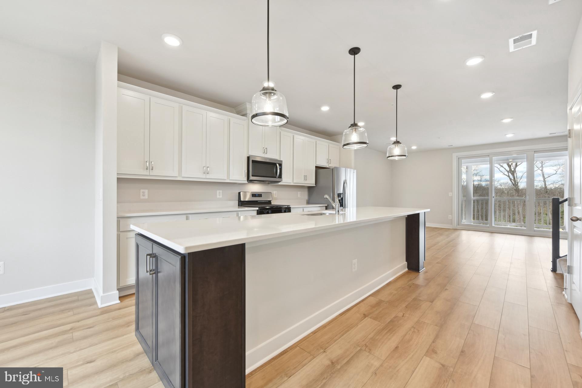 a kitchen with kitchen island a sink a stove and wooden floor