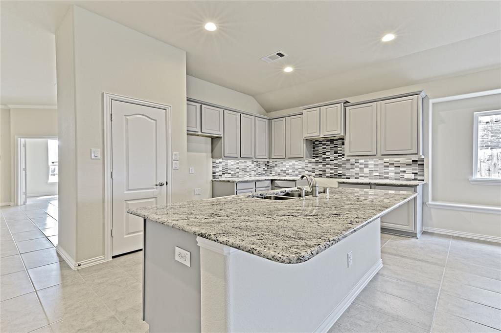 a kitchen with kitchen island granite countertop a sink and refrigerator