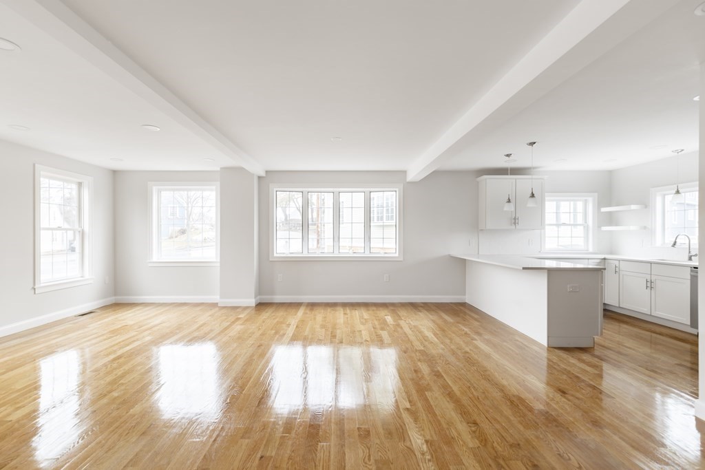 a view of an empty room with window and wooden floor