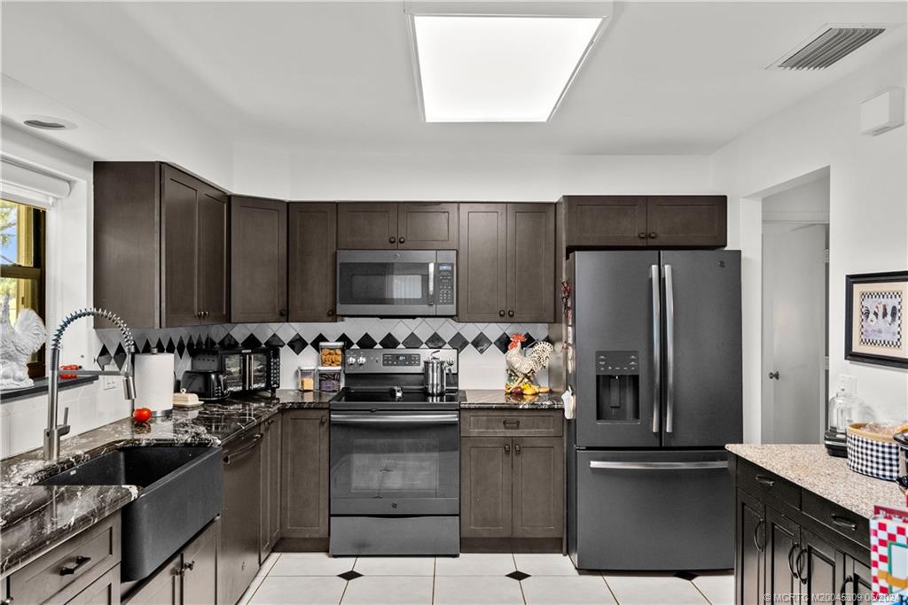 a kitchen with kitchen island granite countertop a sink stove and refrigerator