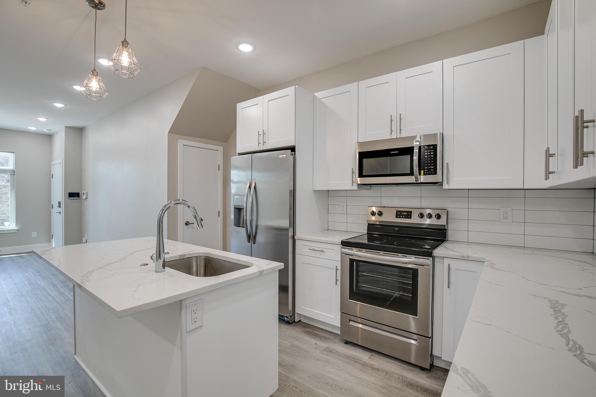 a kitchen with stainless steel appliances a stove a sink a microwave and cabinets