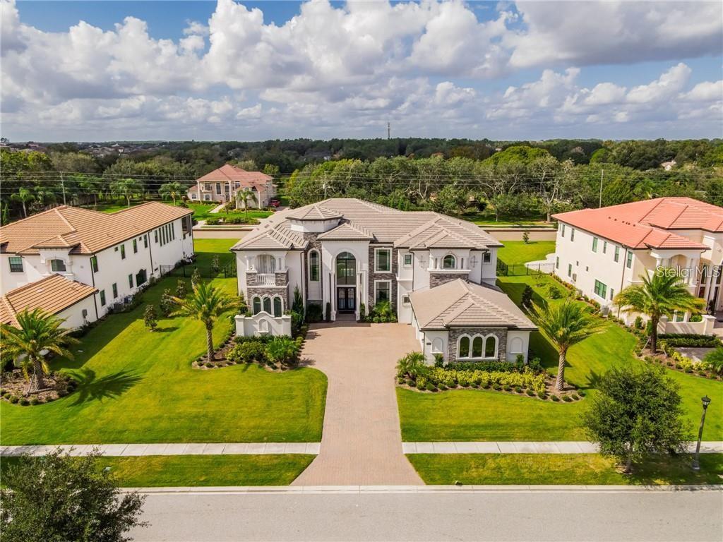 aerial view of a house with a yard and table and chairs under an umbrella