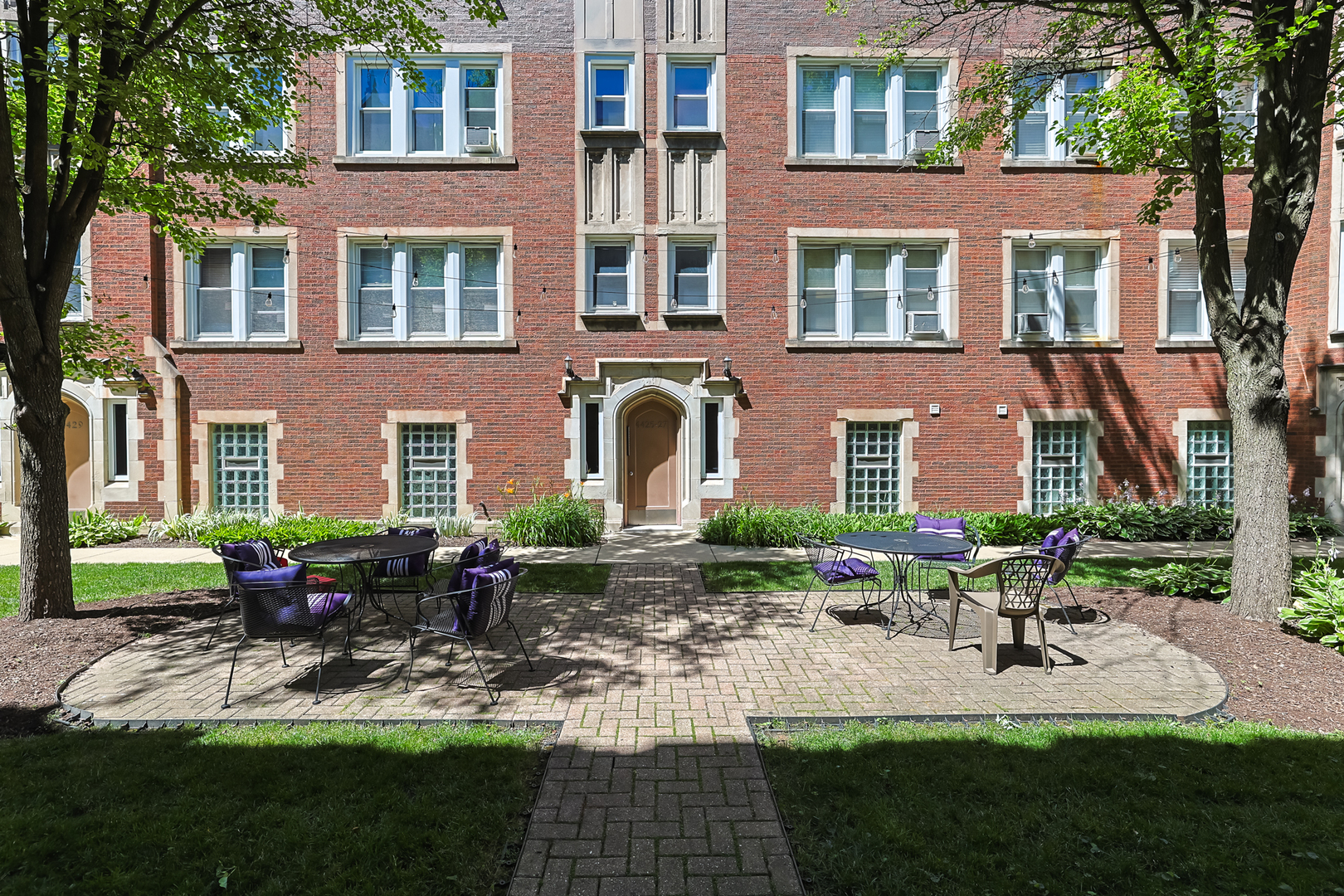 a front view of a building with garden and outdoor seating