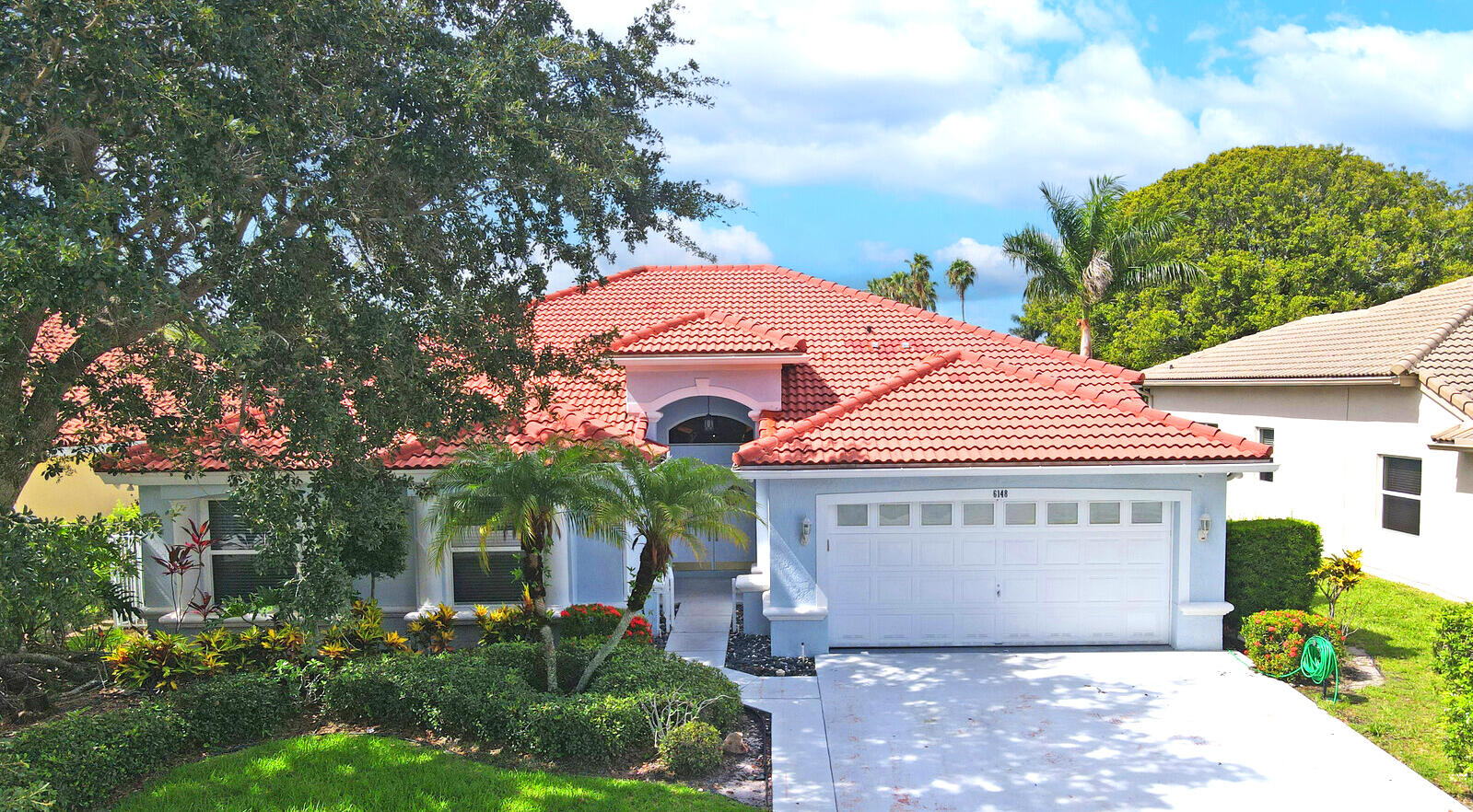 a front view of a house with plants and garage