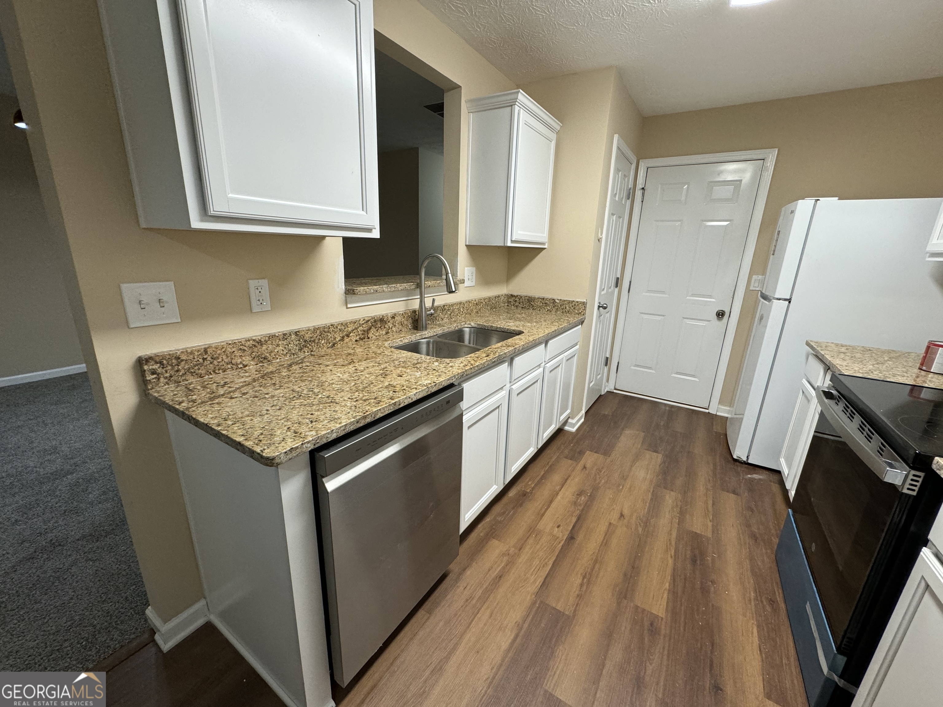 a kitchen with a sink stove and wooden floor