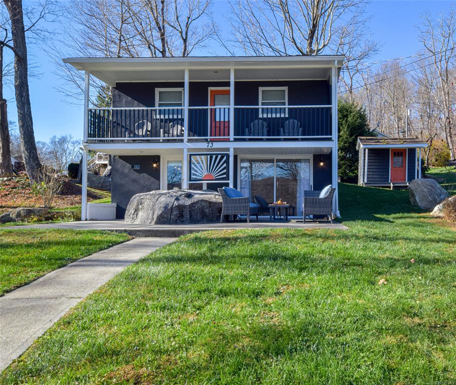 View of front of home featuring storage unit, a patio area, a balcony, and a front yard