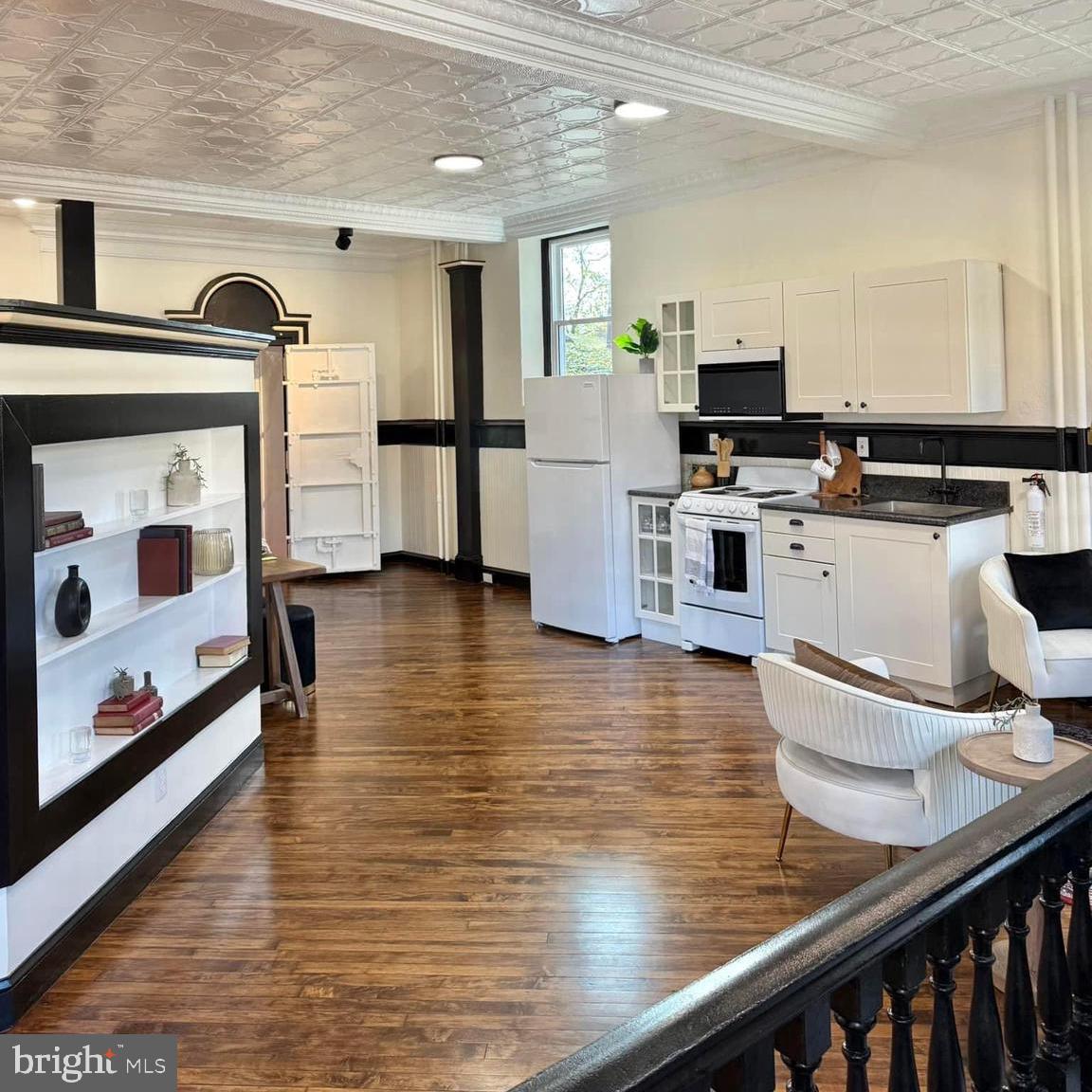 a open kitchen with stainless steel appliances wooden floor and a refrigerator