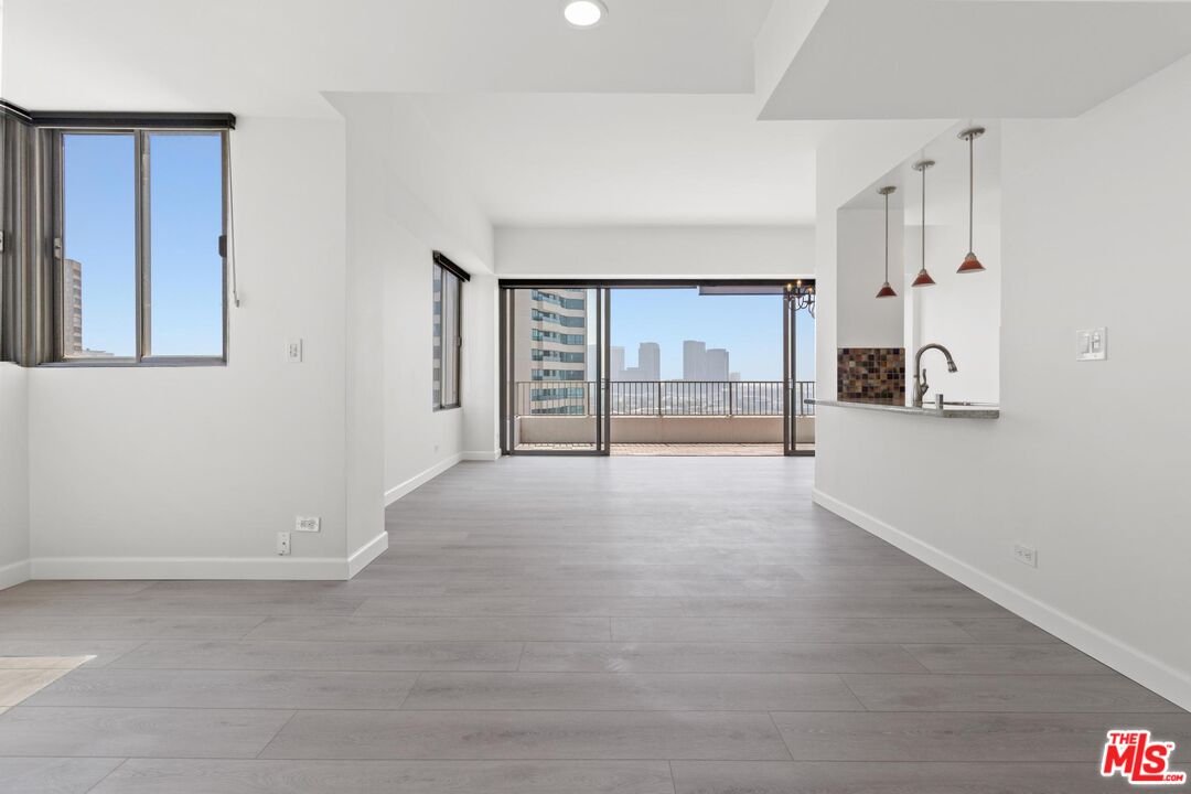 a view of a livingroom with wooden floor and a kitchen space