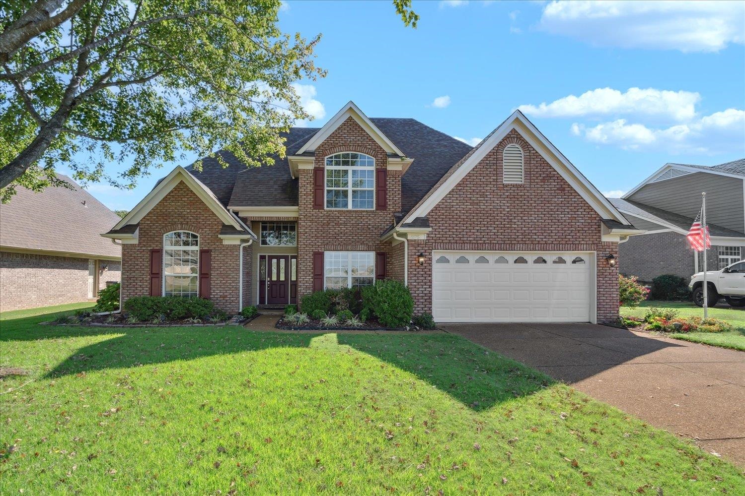 View of front property featuring a garage and a front lawn