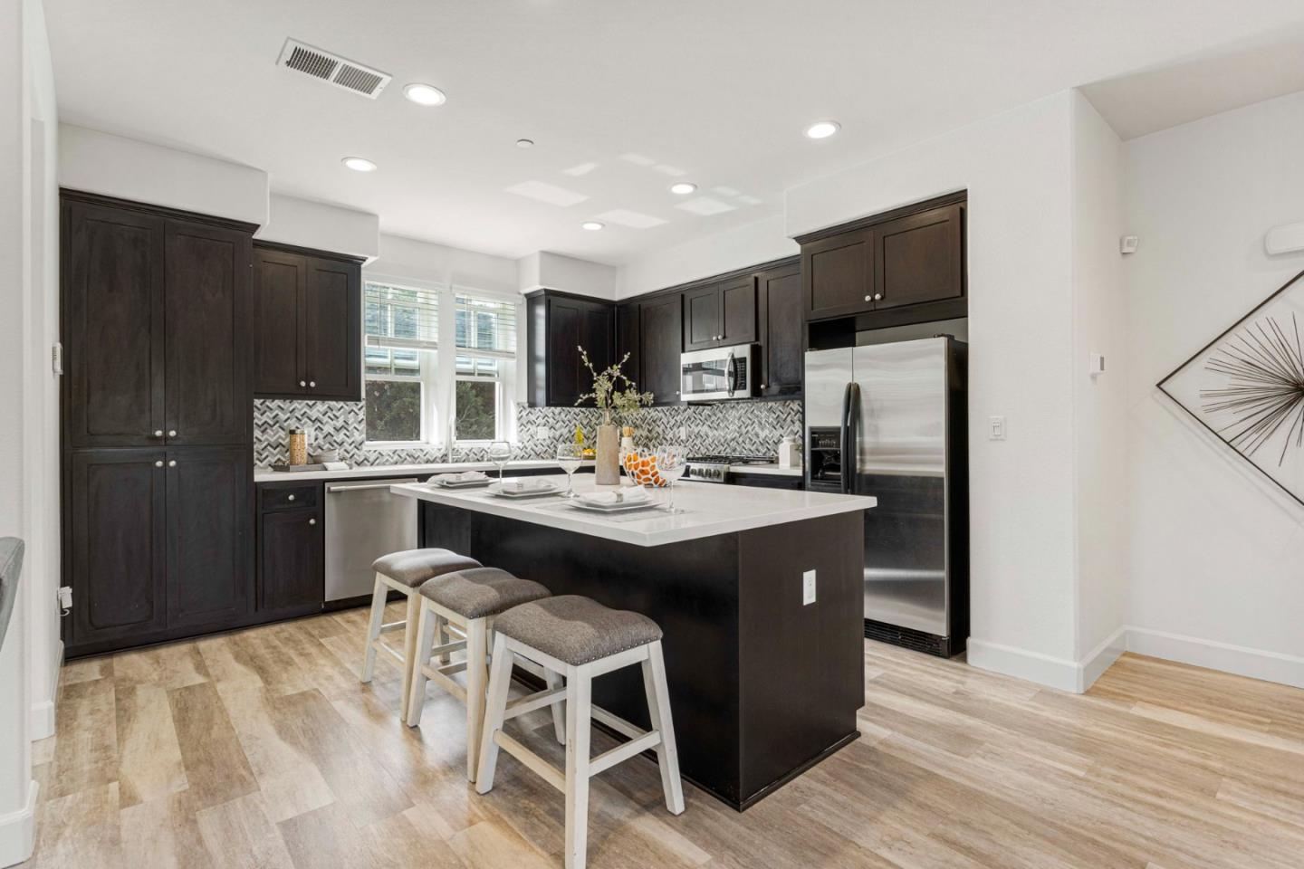 a kitchen with stainless steel appliances kitchen island granite countertop a sink refrigerator and cabinets