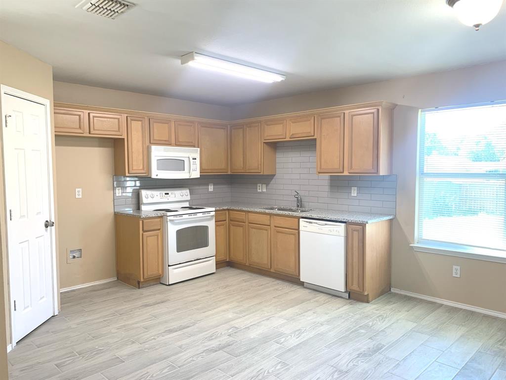 a kitchen with granite countertop white cabinets and white appliances