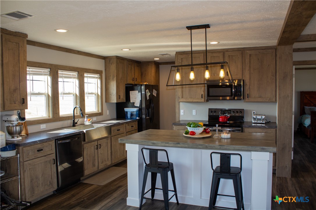 a kitchen with refrigerator a sink and chairs