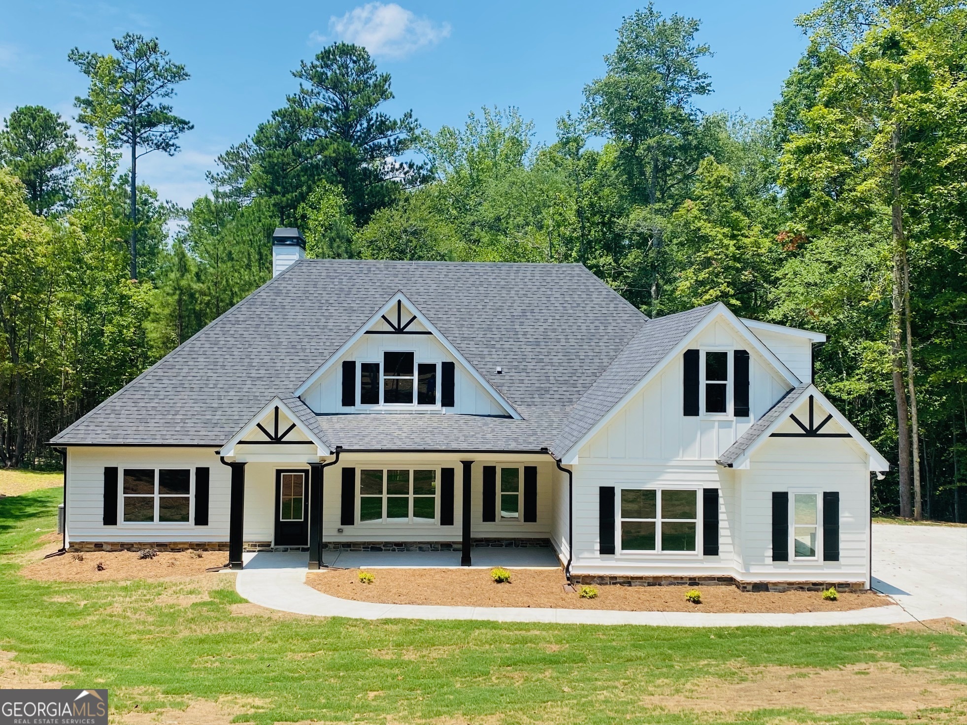 a front view of a house with a garden and trees