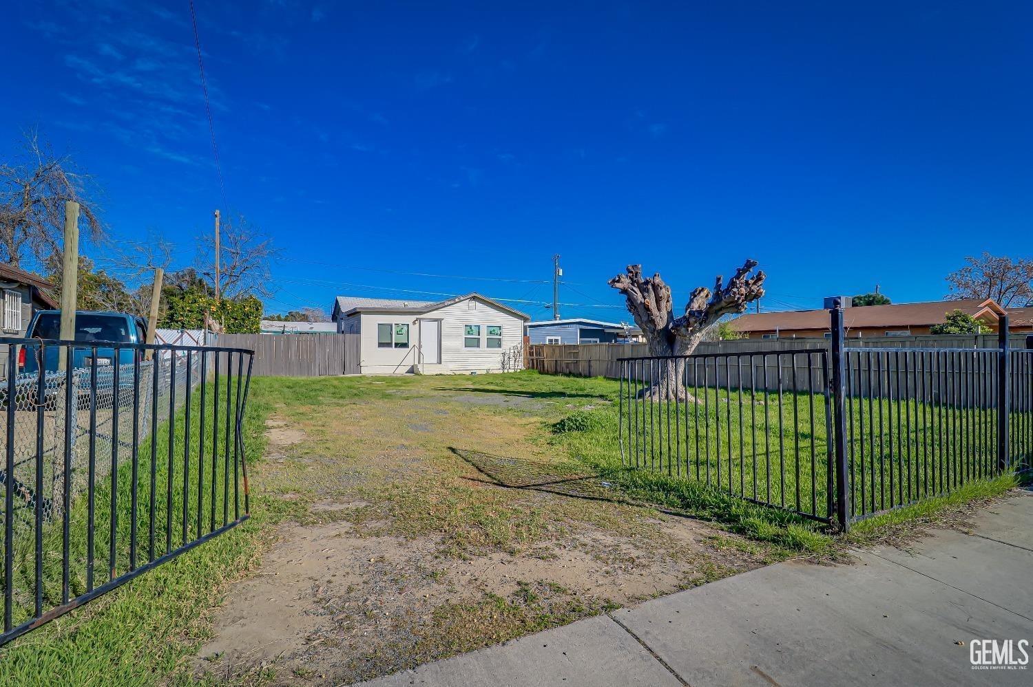 a view of a house with a small yard and a wooden fence