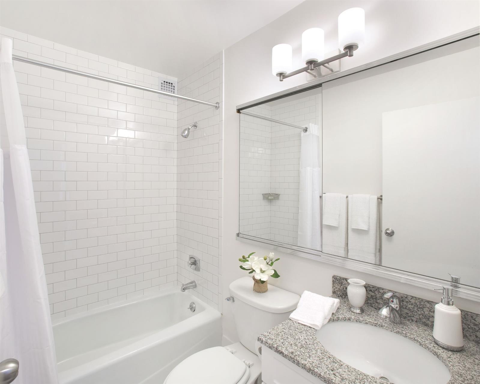 a bathroom with a granite countertop sink mirror toilet and bathtub