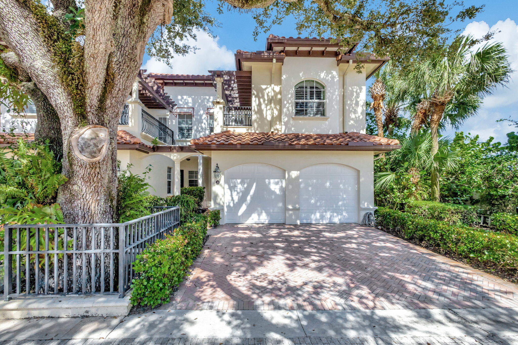 a front view of a house with a garden and trees